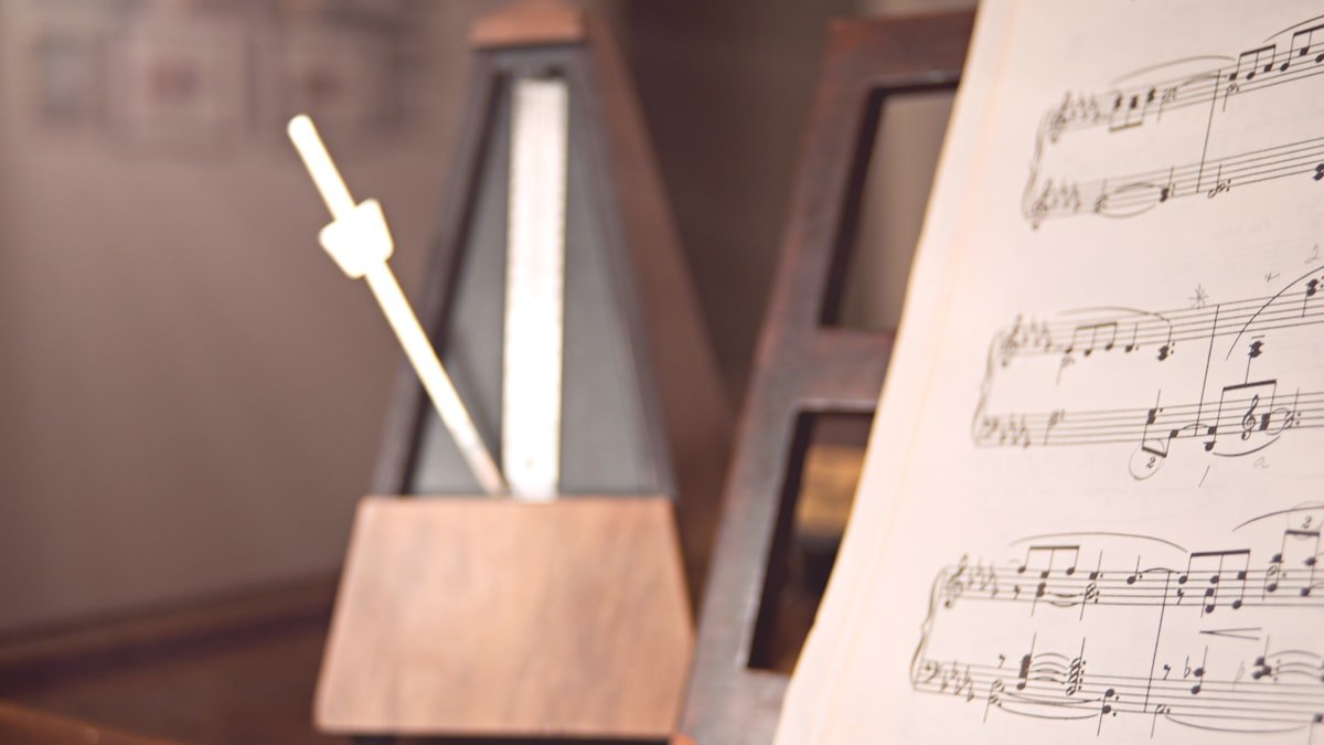 A wooden metronome mid-swing beside sheet music, symbolizing operating cadence and rhythm in execution